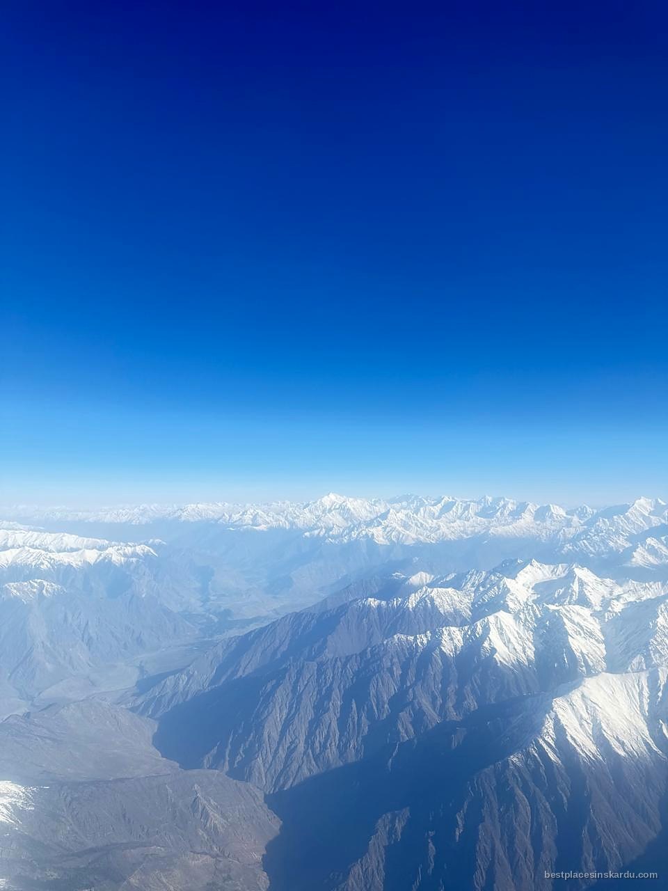 Aerial view of snow-capped Karakoram ranges and a river valley on the Islamabad to Skardu flight