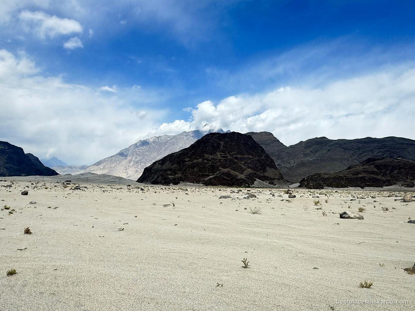 Dark rock outcrop rising from the pale sand of Sarfaranga Cold Desert