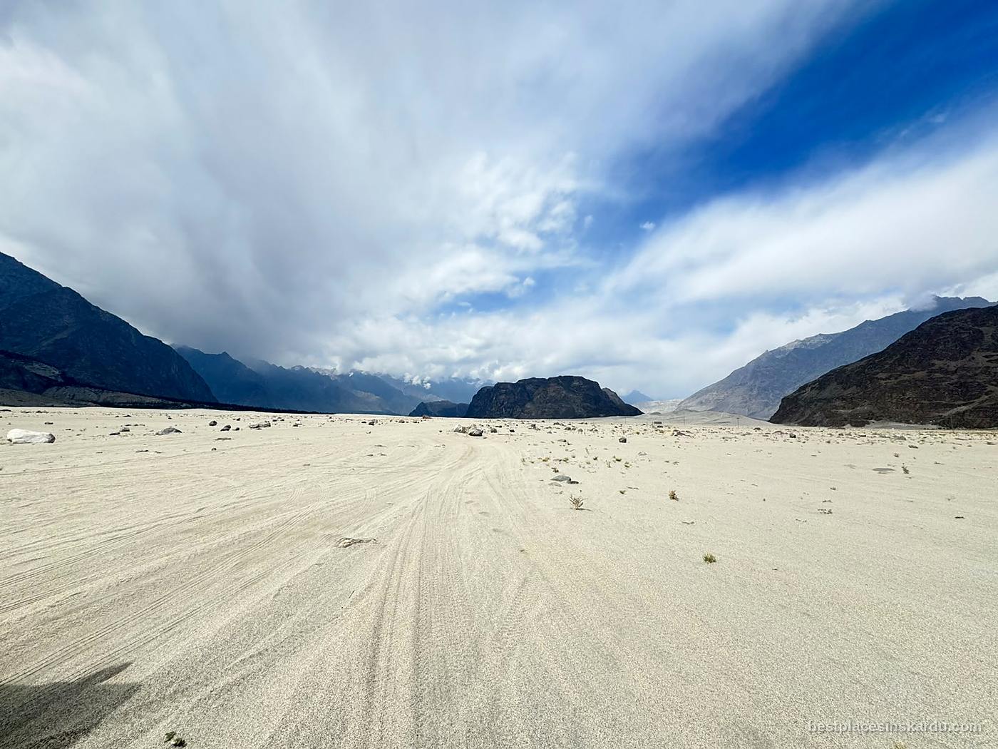 Vehicle tracks across Sarfaranga Cold Desert under heavy cloud near Skardu
