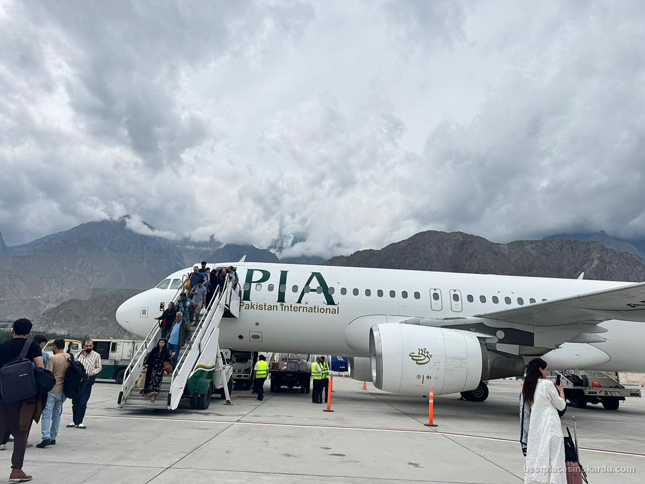 Passengers disembarking a PIA aircraft at Skardu International Airport under heavy cloud